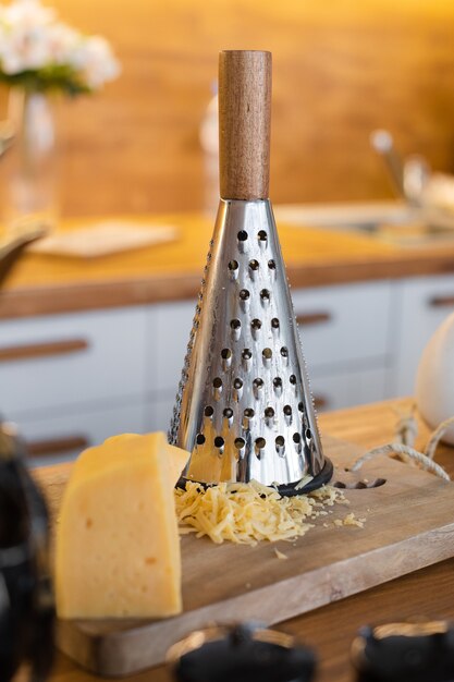 Cheese is on the table near the iron grater, picture of a dinner rable