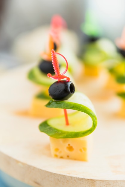 Free photo cheese, olive and cucumber on plastic skewer on plate