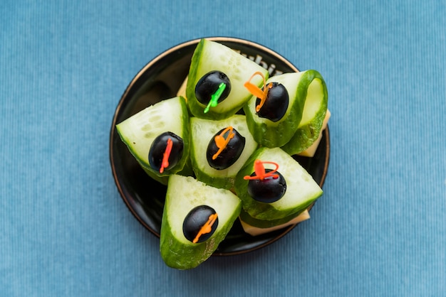 Free photo cheese, olive and cucumber on plastic skewer on saucer