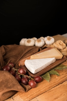 테이블 위에 포도와 마늘 전구 나무 쟁반에 치즈