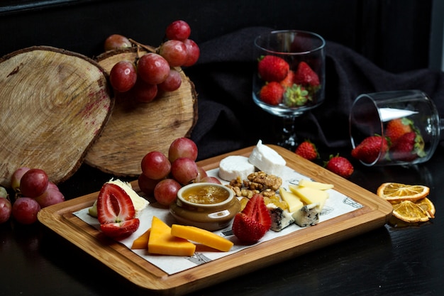 cheese plate with cheddar, white and gouda cheese, strawberry, honey, walnut and grape