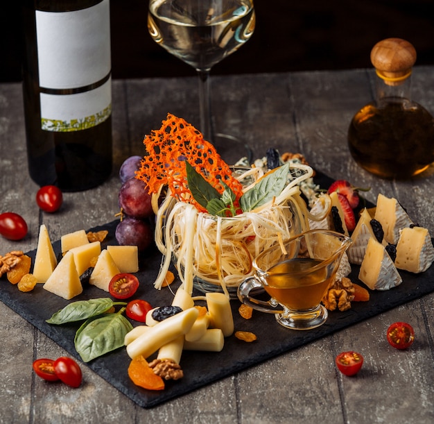 Cheese plate with glass cup of smoked cheese in the middle