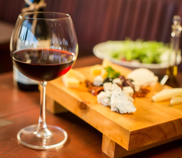 Foto gratuita piatto di formaggi con un bicchiere di vino rosso