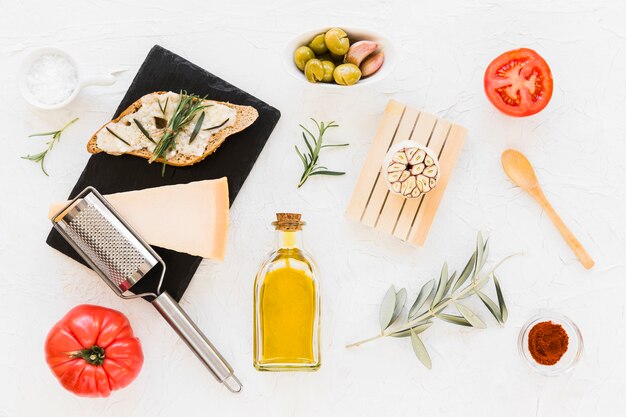 Cheese and rosemary on bread with olives and tomatoes on white background