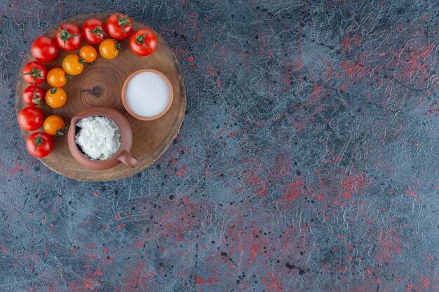 大理石の背景に、ボード上のチーズ、塩、トマト。