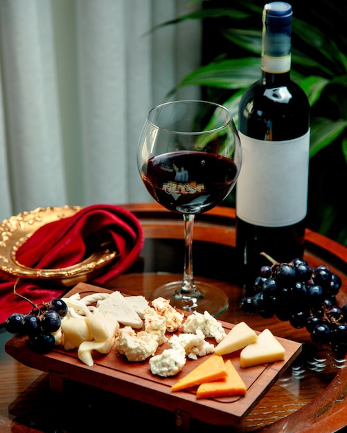 Free photo cheese set with winegrape and glass of wine