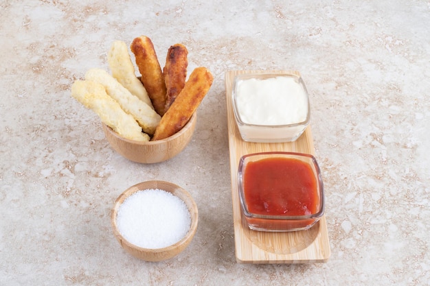 Cheese sticks and grilled sausages in a wooden cup.