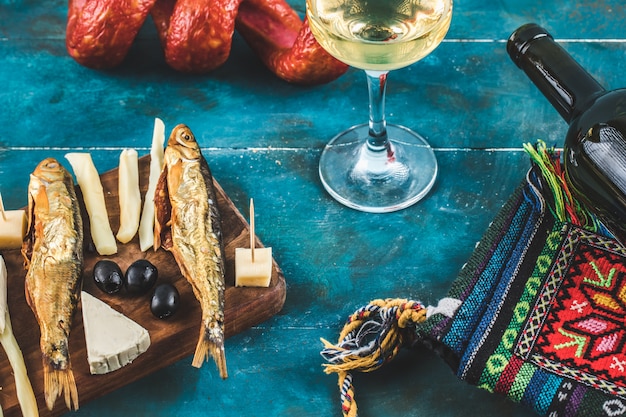 ワインのグラスと青の背景に魚の燻製とチーズスティック