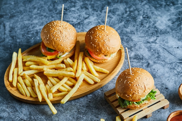 Foto gratuita cheeseburger con patate fritte sulla tavola di legno