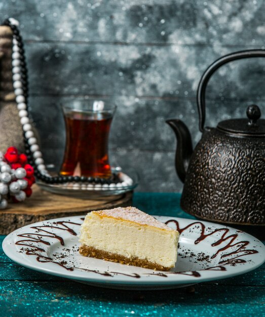 cheesecake slice in white plate served with black tea