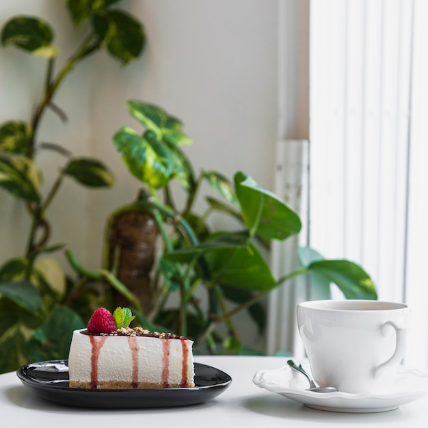 果実とチーズケーキ。植物の近くのカフェのテーブルの上のコーヒーカップ