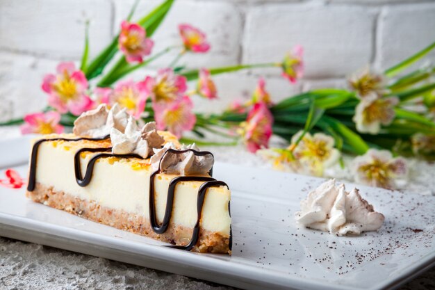 꽃과 하얀 접시에 크림 치즈 케이크