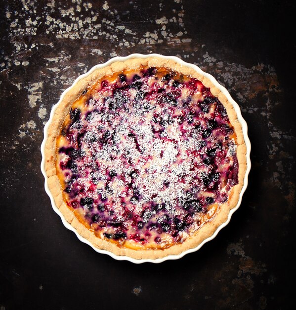 Cheesecake with raspberry on a dark wooden table seen from above