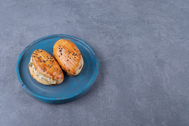 Cheesy pastry on wooden plate on marble table.