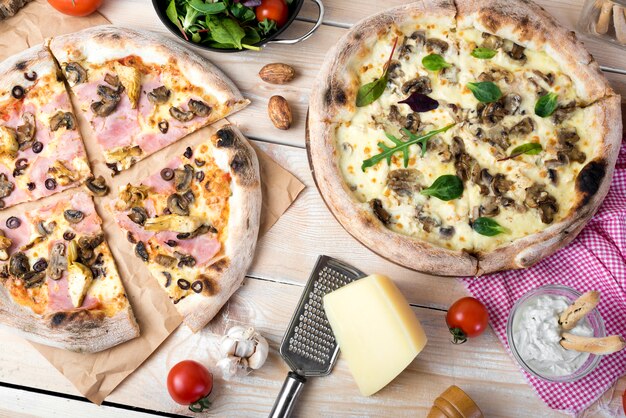 Cheesy pizza; salad with cheese; dip and vegetables over wooden surface