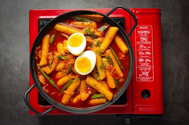 Сырная корейская традиционная еда Tokbokki на фоне черной доски. Обеденное блюдо.