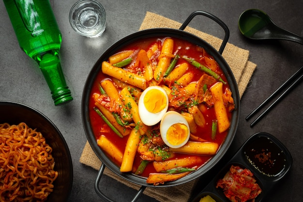 Сырная корейская традиционная еда Tokbokki на фоне черной доски. Обеденное блюдо.