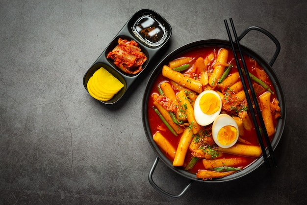 Сырная корейская традиционная еда Tokbokki на фоне черной доски. Обеденное блюдо.