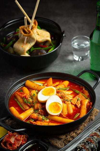 Сырная корейская традиционная еда Tokbokki на фоне черной доски. Обеденное блюдо.