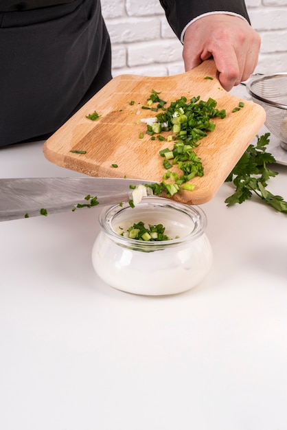 Chef adding chives to salad dressing