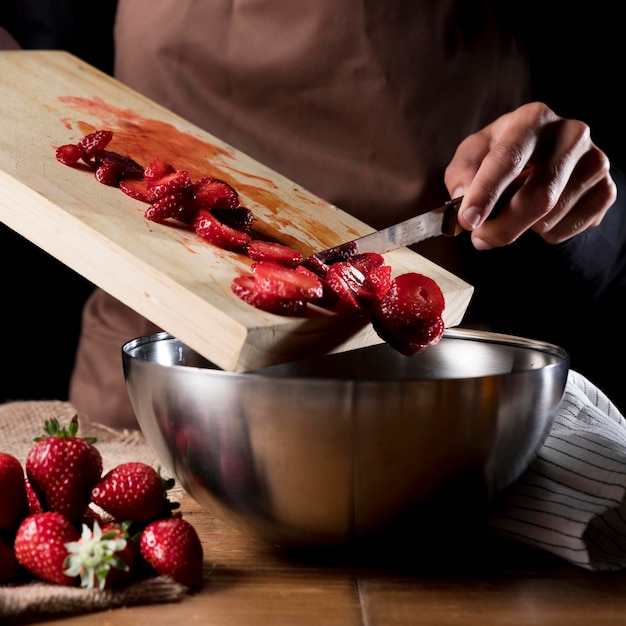Chef adding chopped strawberries to bowl