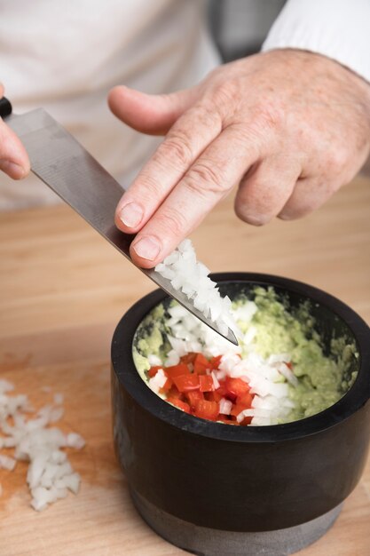 Chef adding onion in guacamole