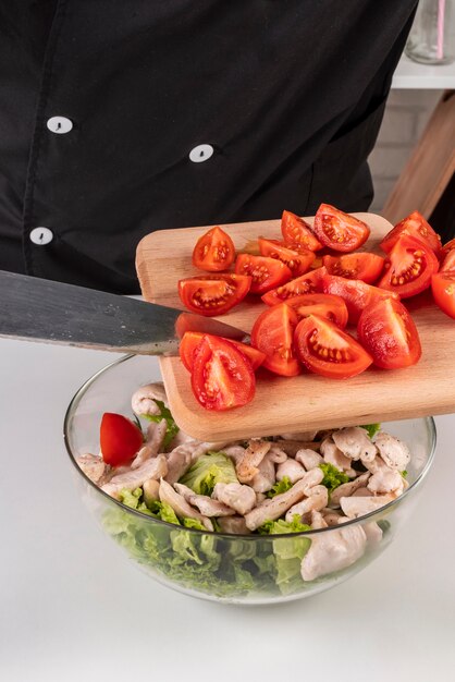 Chef adding tomatoes to meat salad