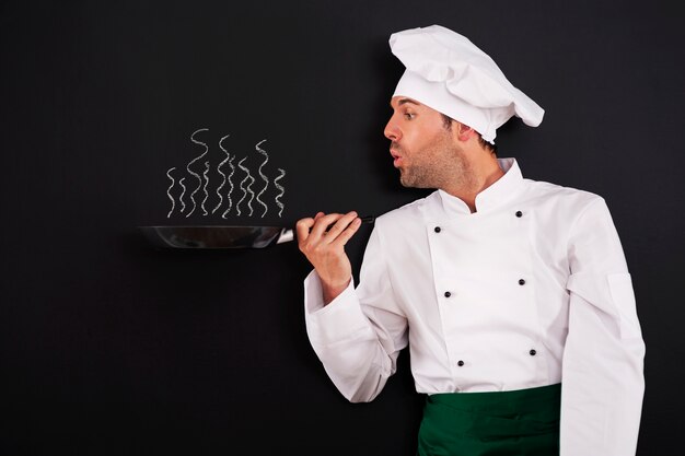 Шеф-повар дует дым из сковороды