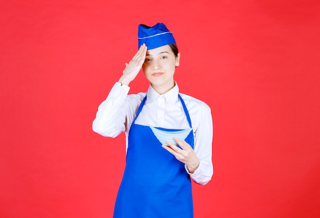 Free photo chef in blue apron holding a ceramic bowl of food and looks tired.