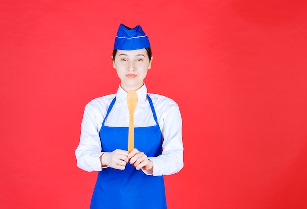 Free photo chef in blue apron holding a wooden spoon.