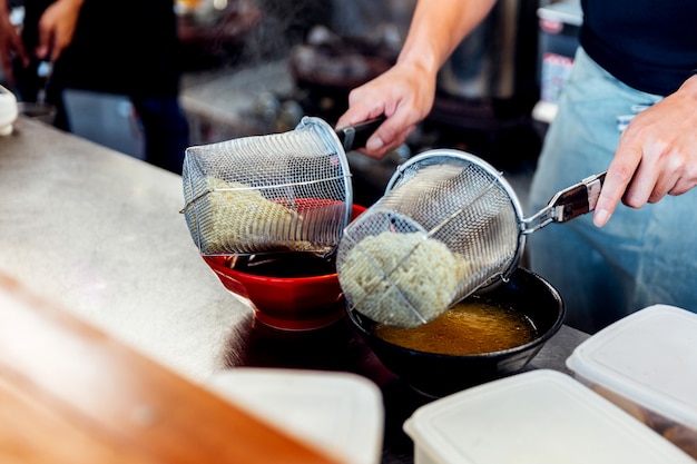 된장과 쇼유라면을 만들기위한 수프에라면을 끓는 요리사. 프리미엄 사진
