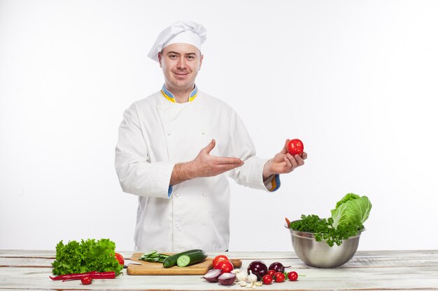 彼のキッチンで新鮮な野菜サラダを調理するシェフ