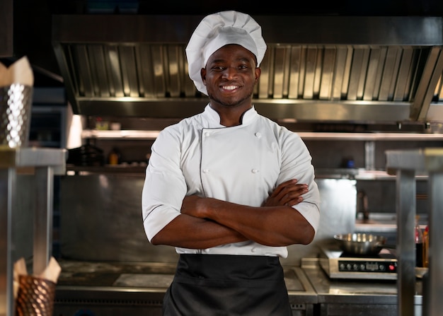 Foto gratuita chef che cucina in cucina indossando abiti professionali