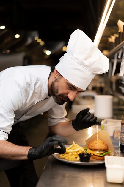 Foto gratuita chef che cucina in cucina indossando abiti professionali