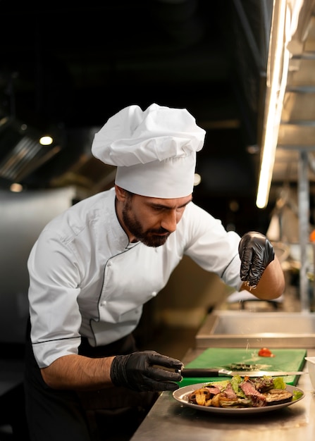 Foto gratuita chef che cucina in cucina indossando abiti professionali