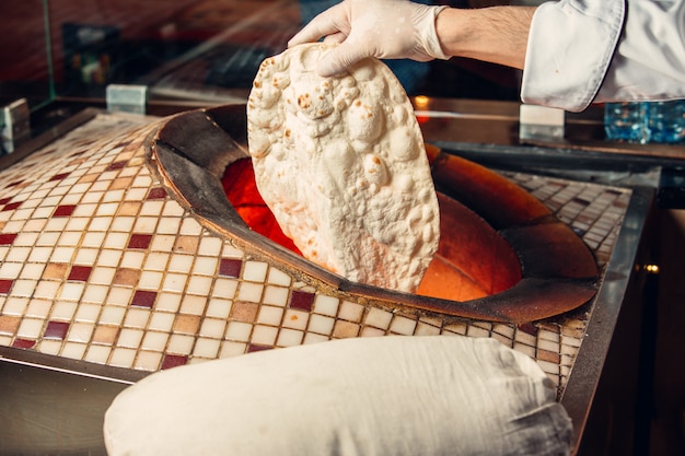 오븐 tandir 안에 lavash 빵을 요리하는 요리사.