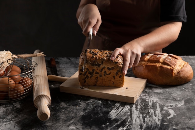 Chef cutting baked bread on chopping board