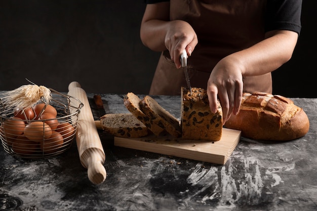 Free photo chef cutting bread loaf on chopping board