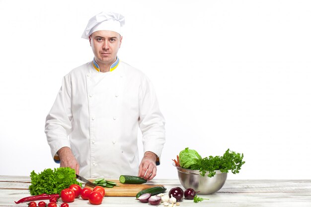 Chef cutting a green cucumber in his kitchen