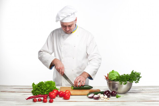 Chef cutting a green cucumber in his kitchen