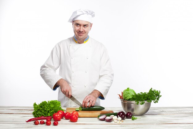 Chef cutting a green cucumber in his kitchen