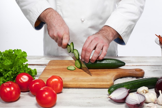 Cuoco unico che taglia un cetriolo verde nella sua cucina