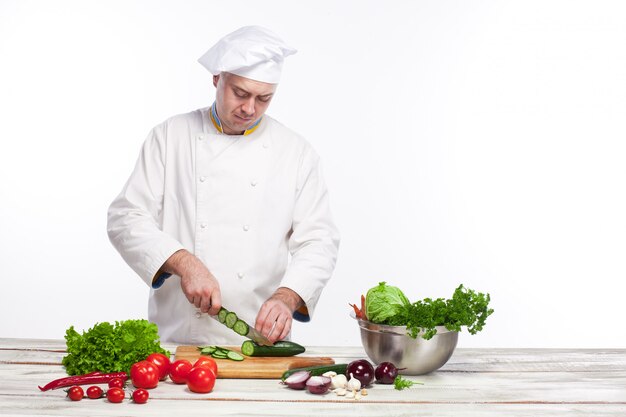 Chef cutting a green cucumber in his kitchen