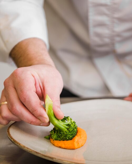 Chef dipping broccoli in sauce