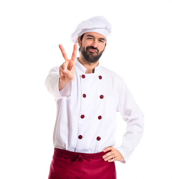 Chef doing victory gesture over white background