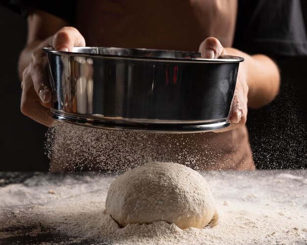 Chef dusting flour over bread dough