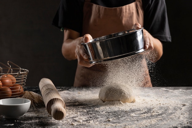 Chef dusting flour over dough