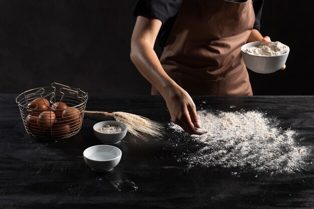 生地をこねるためにテーブルに小麦粉をまぶすシェフ