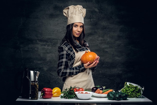 Chef female holds punmping on a dark background.