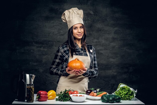 Chef female holds punmping on a dark background.